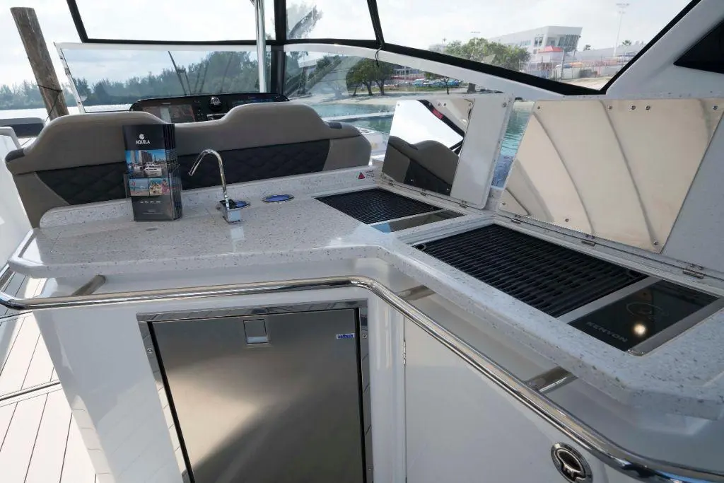 A stylish boat kitchen area featuring a sink, barbecue grill, and a brochure showcasing luxury yachts.